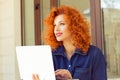 Attractive thoughtful daydreaming young woman holding open notebook, looking aside, smiling, sitting outdoor. Portrait in profile