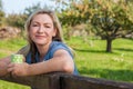 Attractive Thoughtful Middle Aged Woman Resting on Fence With Mug of Coffee or Tea