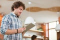 Attractive thoughtful smiling curly young male using tablet at home Royalty Free Stock Photo