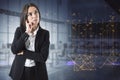 Attractive thoughtful young european business woman with abstract polygonal lines hologram standing on blurry office interior