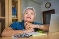 Attractive and tired middle aged Asian woman working at laptop computer desk confident daydreaming absent minded thinking about Royalty Free Stock Photo