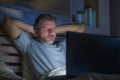 Attractive tired and stressed workaholic man working late night exhausted on bed busy with laptop computer sleepy and overworked Royalty Free Stock Photo