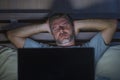 Attractive tired and stressed workaholic man working late night exhausted on bed busy with laptop computer sleepy and overworked Royalty Free Stock Photo