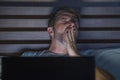 Attractive tired and stressed workaholic man working late night exhausted on bed busy with laptop computer yawning feeling sleepy Royalty Free Stock Photo