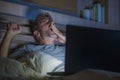 Attractive tired and stressed workaholic man working late night exhausted on bed busy with laptop computer yawning feeling sleepy Royalty Free Stock Photo