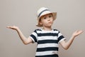 attractive toddler in a straw hat and striped T-shirt looks at the camera in surprise, a studio portrait of a child on