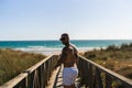 Attractive topless man with tattoos walking on a wooden boardwalk next to a sea