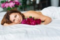 attractive topless woman with a bouquet of peonies on the bed. Royalty Free Stock Photo