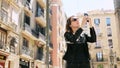 Attractive tourist woman making a selfie uses a smartfone while walking at the street.