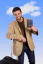 Attractive traveler man leaning on luggage case holding passport smiling happy and confident