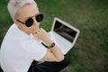 Attractive trendy happy hipster young woman with notebook in hat and sunglasses have fun in the park on the grass. Royalty Free Stock Photo