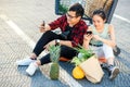 Attractive vietnamese boy and beauiful girl sitting on the parking near shopping mall and uses their smartphones. Royalty Free Stock Photo