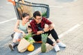 Attractive vietnamese boy and beauiful girl sitting on the parking near shopping mall and uses their smartphones. Royalty Free Stock Photo