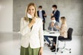 Attractive vusiness woman taking off her protective facial mask and looking at the camera with her team members sitting in Royalty Free Stock Photo