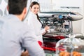 Attractive waitress smiling to male customer while preparing esp