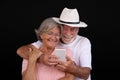 Attractive white-haired senior couple embraced using mobile phone. Two happy retirees enjoying free time and technology, new young Royalty Free Stock Photo