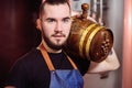 Attractive winemaker holds a wooden barrel of wine