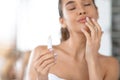 Attractive Woman Applying Lipstick Touching Lips Moisturizing Skin In Bathroom Royalty Free Stock Photo