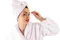 Attractive woman in bathrobe plucks eyebrows