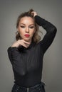 Attractive woman in black blouse and red lips posing challenging in front of a background. Royalty Free Stock Photo