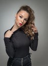 Attractive woman in black blouse and red lips posing challenging in front of a background. Royalty Free Stock Photo