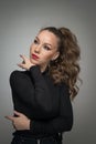 Attractive woman in black blouse and red lips posing challenging in front of a background. Royalty Free Stock Photo