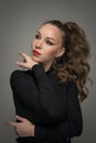 Attractive woman in black blouse and red lips posing challenging in front of a background. Royalty Free Stock Photo