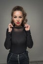 Attractive woman in black blouse and red lips posing challenging in front of a background. Royalty Free Stock Photo