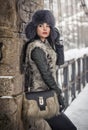 Attractive woman with black fur cap and gray waistcoat enjoying the winter. Side view of fashionable brunette girl posing Royalty Free Stock Photo