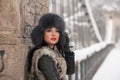 Attractive woman with black fur cap and gray waistcoat enjoying the winter. Side view of fashionable brunette girl posing Royalty Free Stock Photo