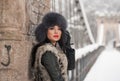 Attractive woman with black fur cap and gray waistcoat enjoying the winter. Side view of fashionable brunette girl posing Royalty Free Stock Photo