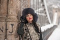Attractive woman with black fur cap and gray waistcoat enjoying the winter. Side view of fashionable brunette girl posing Royalty Free Stock Photo