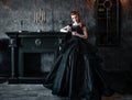 Attractive woman in black dress in medieval interior