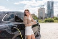 Woman charging an EV car in an electric vehicle parking lot