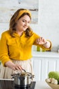 attractive woman checking time on wristwatch near pan on electric stove