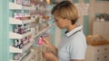 Attractive woman customer buying nail polish in makeup section. Girl in supermarket.