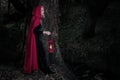 Attractive woman dressed a little red riding-hood walk in a dark forest with lantern Royalty Free Stock Photo