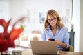 Attractive woman with earphones and mobile phone using laptop at home Royalty Free Stock Photo