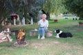 The attractive woman eats fried eggs at the campfire, her dog is watching