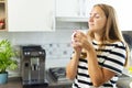 Attractive woman enjoying freshly made coffee in the kitchen in the morning