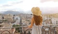 Attractive woman enjoys view of Palermo cityscape from a rooftop terrace, Italy