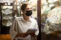 Woman in mask looking at the exposition of antique hand fan at museum