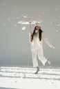 attractive woman in fashionable winter sweater and scarf jumping under paper umbrella, snow falling Royalty Free Stock Photo