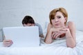 Attractive woman feeling upset unsatisfied and frustrated in bed with his husband while the man work on computer laptop ignoring h