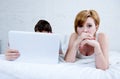 attractive woman feeling upset unsatisfied and frustrated in bed with his husband while the man work on computer laptop ignoring h