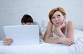 attractive woman feeling upset unsatisfied and frustrated in bed with his husband while the man work on computer laptop ignoring h