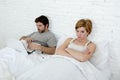 attractive woman feeling upset unsatisfied and frustrated in bed with his husband while the man work on computer laptop ignoring h Royalty Free Stock Photo