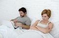 attractive woman feeling upset unsatisfied and frustrated in bed with his husband while the man work on computer laptop ignoring h