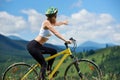 Young happy woman riding bicycle in the mountains at summer day Royalty Free Stock Photo