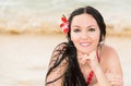 Attractive woman with flower in long hair in bikini on tropical beach sunbathing. Royalty Free Stock Photo